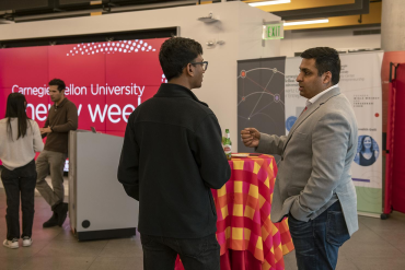 Two people stand and speak together at a networking event